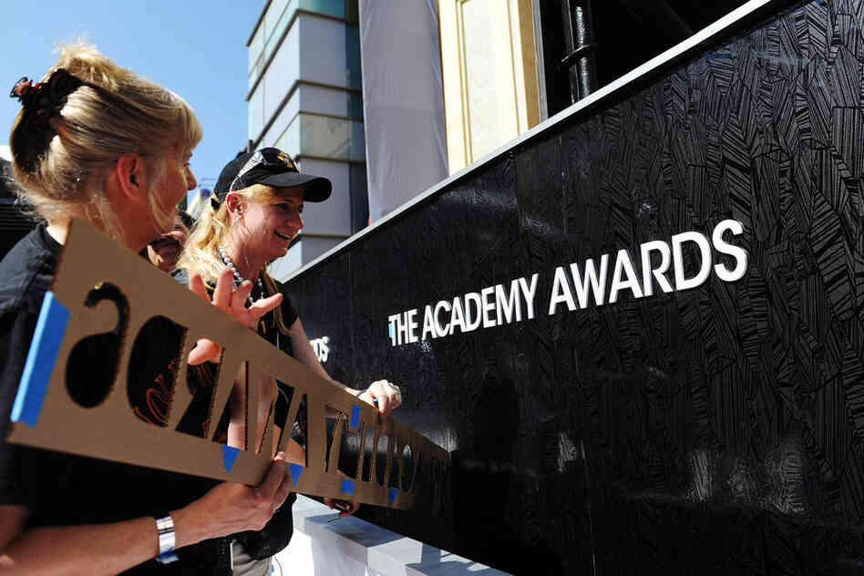 Crew members apply a fixture onto a wall of the red carpet for this year's Academy Awards hosted by Billy Crystal. 