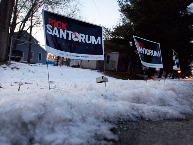 Polls show Rick Santorum and Mitt Romney in a tight race heading into Tuesday's Michigan primary. Santorum's campaign signs are stuck in the snow before his campaign stop at the The Colonial Valley Suites on Feb. 26 in Davison, Mich. 