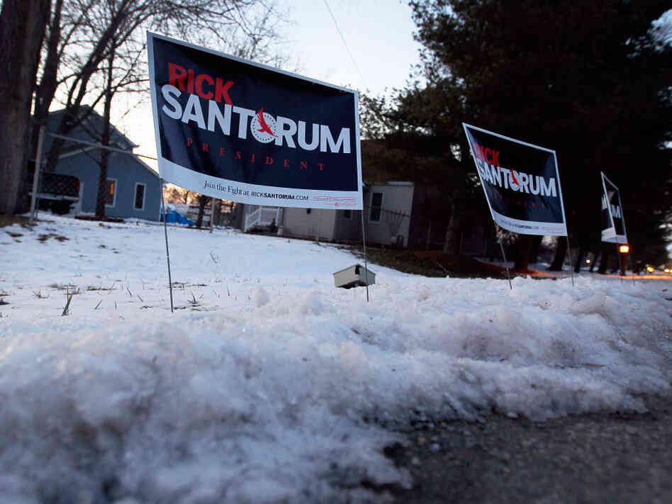 Polls show Rick Santorum and Mitt Romney in a tight race heading into Tuesday's Michigan primary. Santorum's campaign signs are stuck in the snow before his campaign stop at the The Colonial Valley Suites on Feb. 26 in Davison, Mich. 