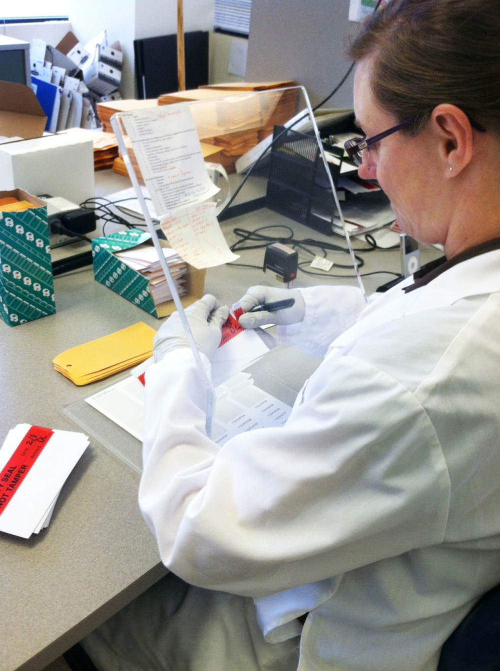 A Washington State Patrol crime lab technician opens DNA sample cards containing cheek swabs sent from jails and prisons. If the state Legislature approves pre-conviction DNA sampling, the number of cards the lab processes could double.