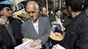An Iranian man passes out election leaflets after Friday prayers in Tehran last week.