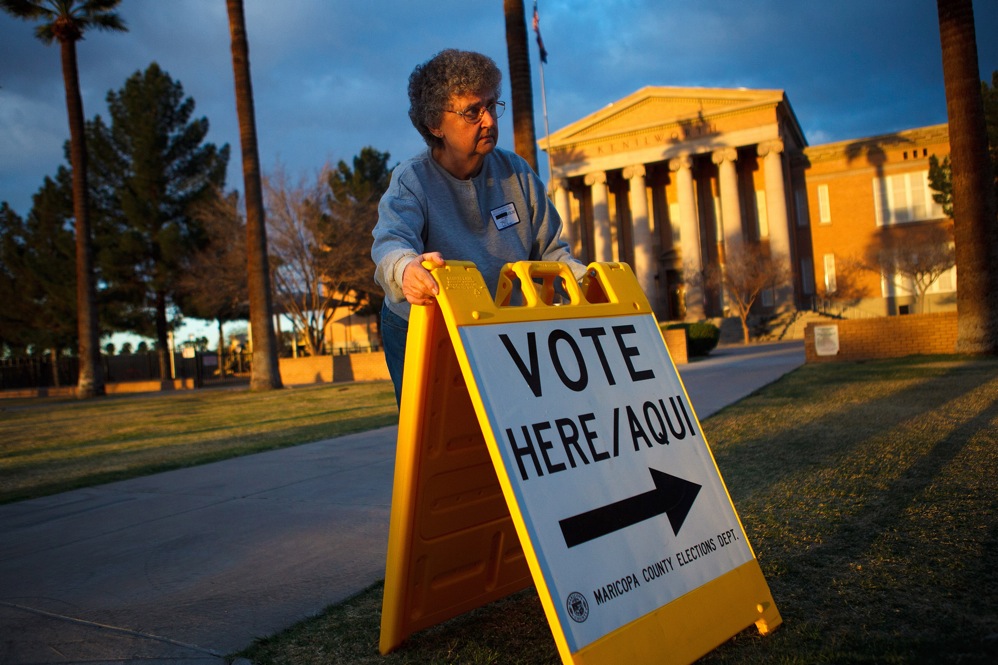 Volunteer Vicki Groff points voters to the polls in Phoenix. Romney won 47.3 percent of the vote in Arizona; Santorum got 26.6. 