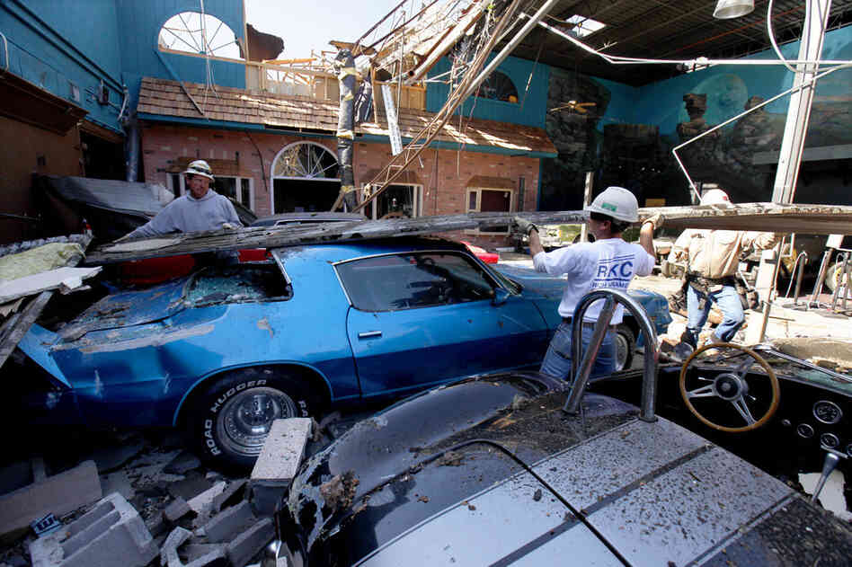 Construction workers lift a piece of sheet metal off cars in a display room at Branson Auto World in Branson, Mo. 