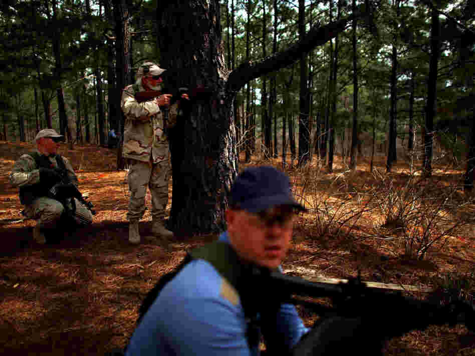 Role players from the Afghan National Army, in tan, and Afghan National Police, in blue, take up positions during a training exercise in a mock Afghan village in Fort Polk, La.