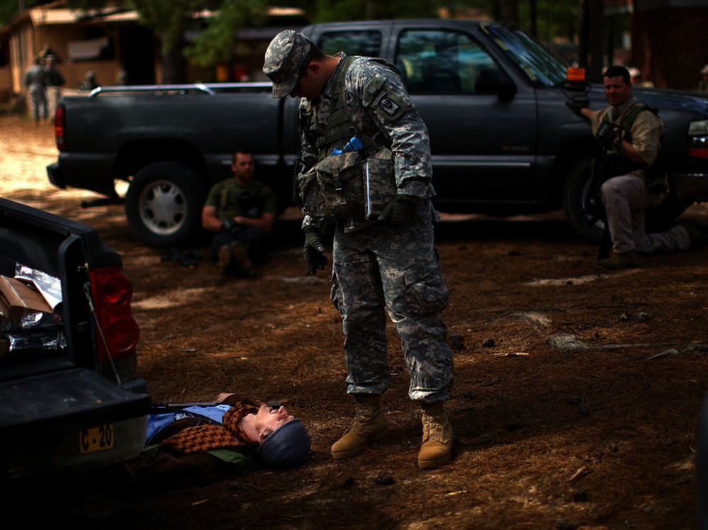 A U.S. Army trainer examines the scene after a mock battle. The man on the ground was playing the role of an Afghan policeman.