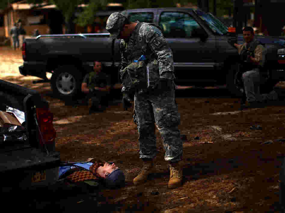 A U.S. Army trainer examines the scene after a mock battle. The man on the ground was playing the role of an Afghan policeman.