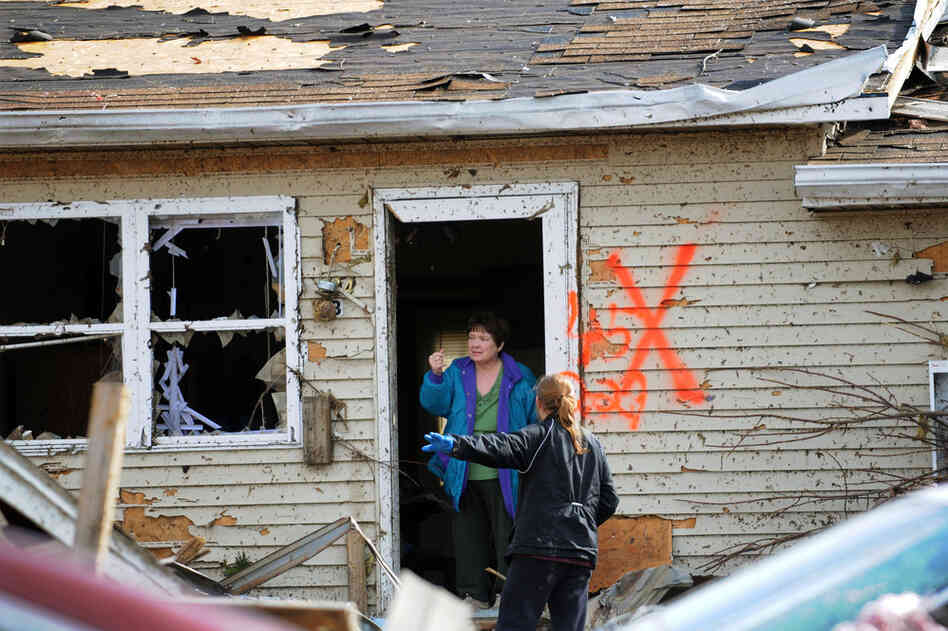 Margaret Shimkus talks with an emergency responder at her home in Harrisburg. Shimkus took refuge in her bathtub during the storm. 