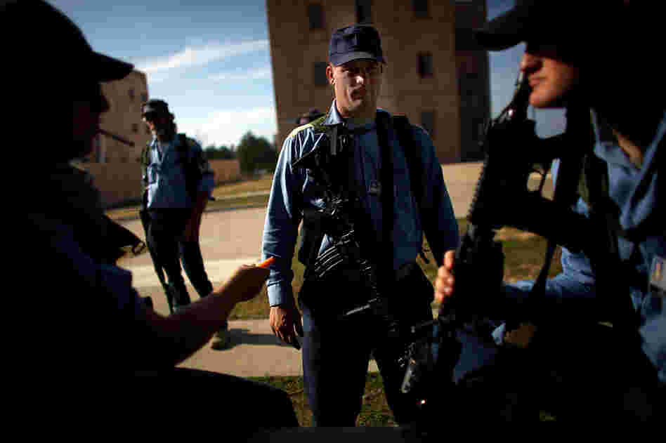 Afghan police role-players (in blue shirts) gather in a mock village. The scenarios are staged to help prepare U.S. soldiers for training the Afghan forces.