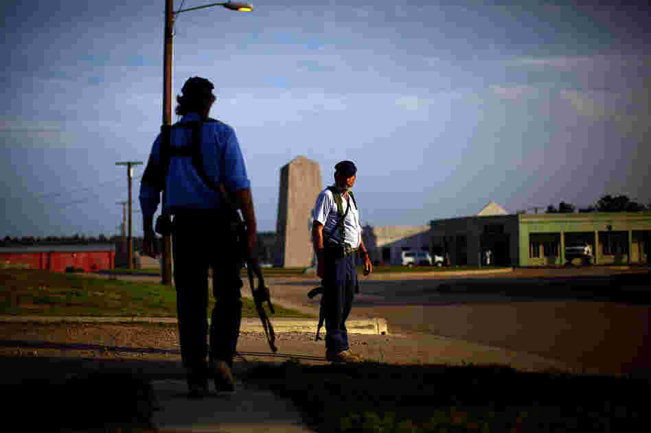 Afghan police role-players, equipped with AK-47 assault rifles, walk the streets of the mock village during a security patrol.