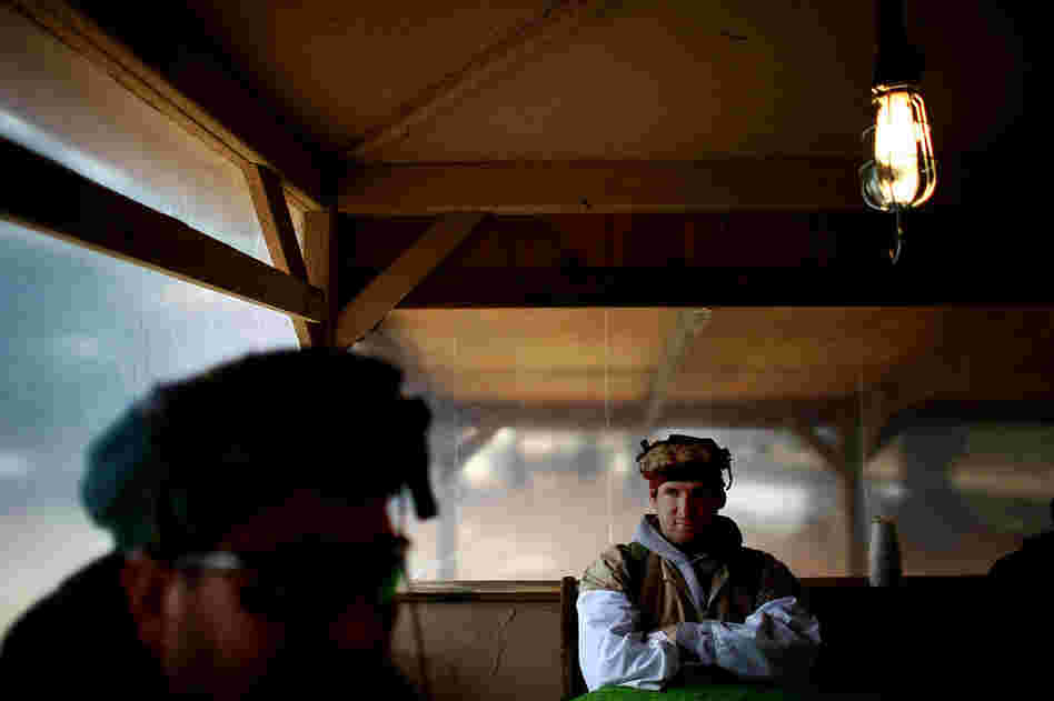 Dressed in traditional clothing, an Afghan role-player waits for a shura — meeting — to end.