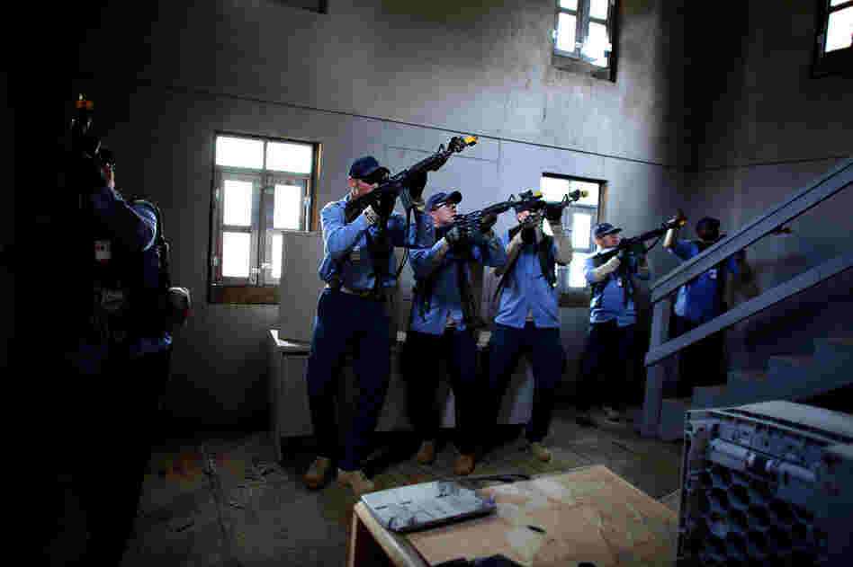 Role-players dressed as Afghan policemen clear a mosque in the mock village where a sniper had been firing at them.