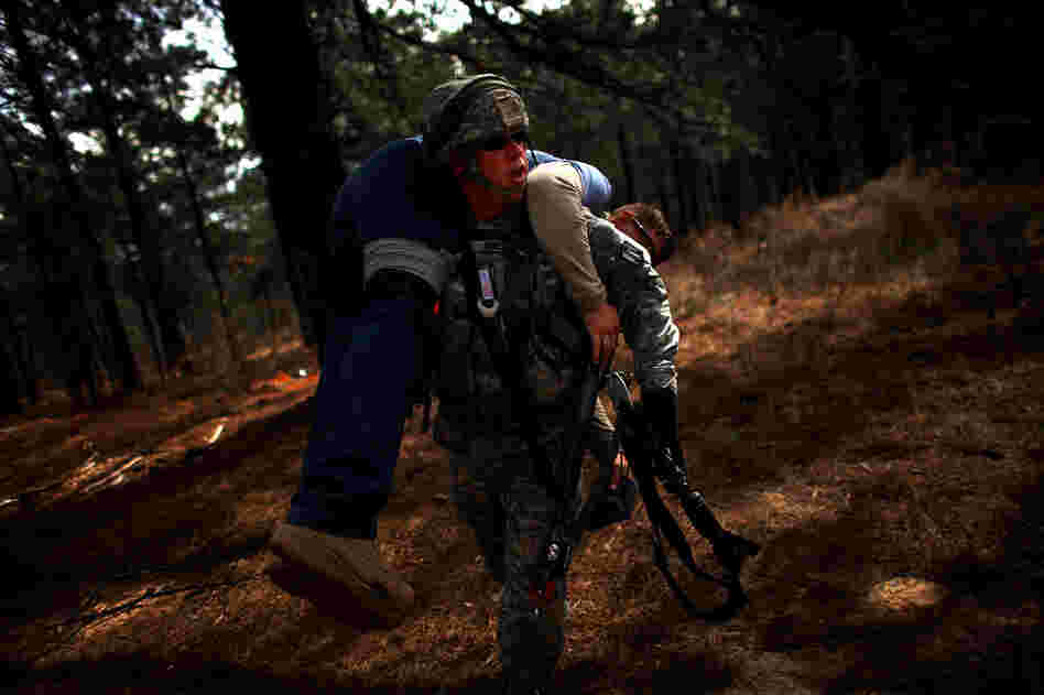 A U.S. soldier carries a wounded Afghan policeman from the battlefield after he was shot during a mock gun battle.