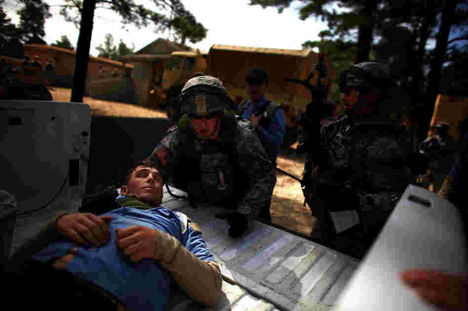 A U.S. soldier puts a wounded Afghan policeman in to the back of a truck after he was shot during a mock gun battle.