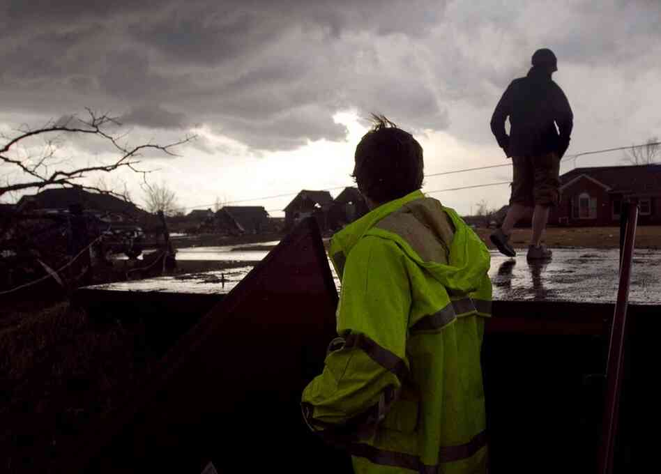 A worker emerges from a shelter to see if there is any new damage to an area already hit by a tornado, in Athens, Ala., on Friday. 