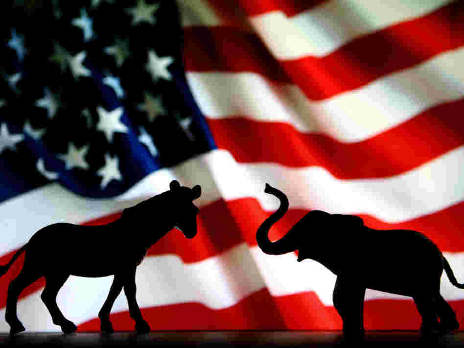 The symbols of the two political parties, the donkey for the Democrats and the elephant for the Republicans, battle it out in front of the American flag. 