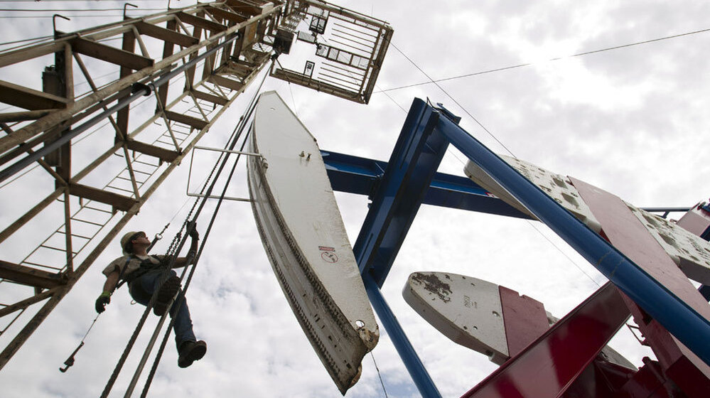A worker hangs from an oil derrick near Williston, N.D. The state now produces 500,000 barrels of crude oil per day, and production continues to rise. 