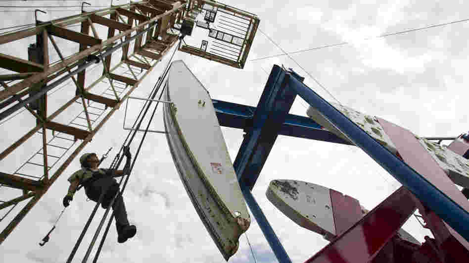 A worker hangs from an oil derrick near Williston, N.D. The state now produces 500,000 barrels of crude oil per day, and production continues to rise. 