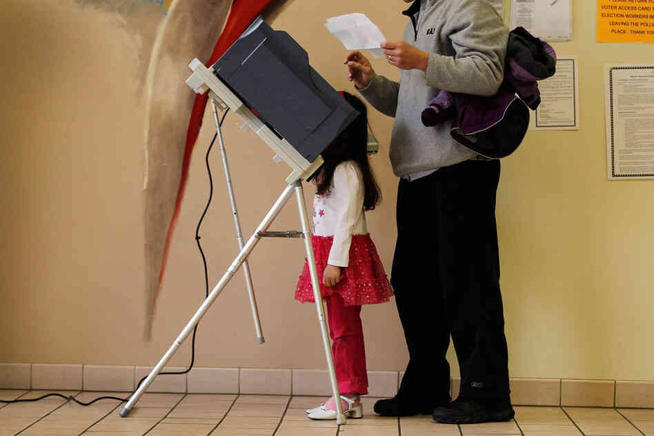 Sophia Walsh, 5, watches as her father, William Walsh, fills out his ballot in Steubenville, Ohio. 