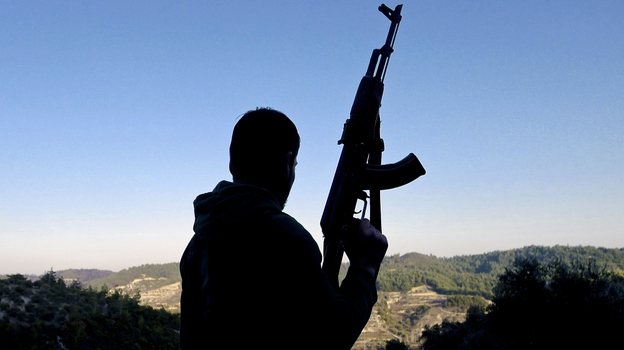 A member of the Free Syrian Army looks at the valley in the village of Ain al-Baida, in Syria's Idlib province, near the Turkish border, in December. Syrians fleeing the fighting in their country are flowing out across the border with Turkey, but opposition fighters say very few weapons are flowing in.