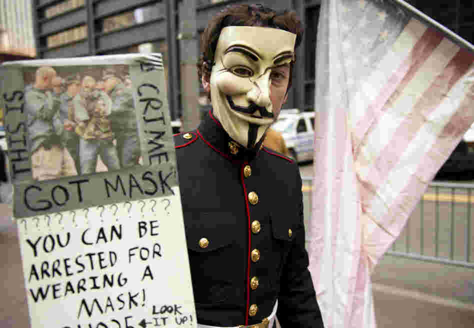 A young man with wearing a military uniform and mask usually associated with the group anonymous marches with Occupy Wall Street protesters in this November.