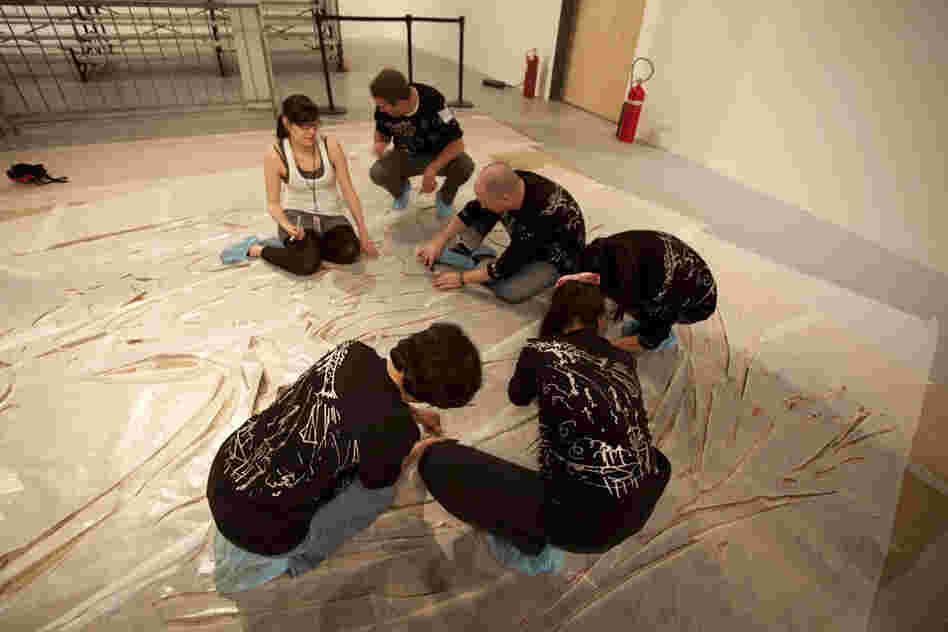 Before the explosion, volunteers help prepare the enormous canvases with cardboard stencils.