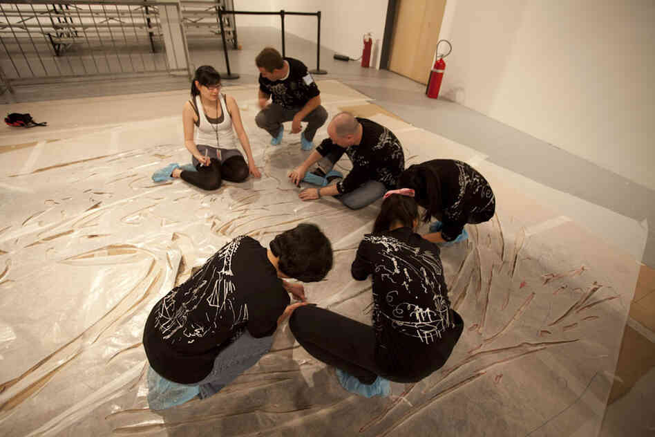 Before the explosion, volunteers help prepare the enormous canvases with cardboard stencils.