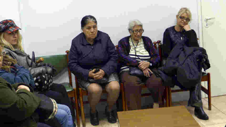 Patients sit in the waiting room of a free medical clinic in Perama, Greece, run by an international aid group, Doctors of the World, last month. Official unemployment in the port town is 80 percent, and many people are unable to afford food and medicine.