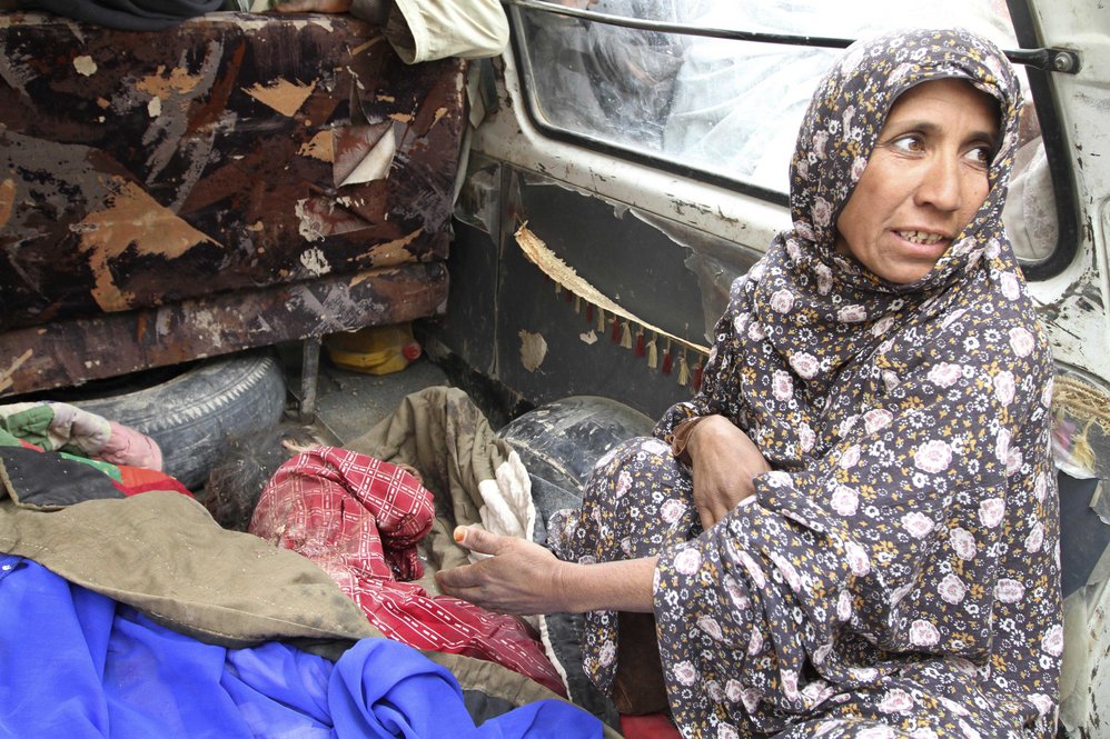 As one woman spoke to reporters, she pulled back a blanket to reveal the body of a smaller child. A third dead child lay amid a pile of green blankets in the bed of a truck. 