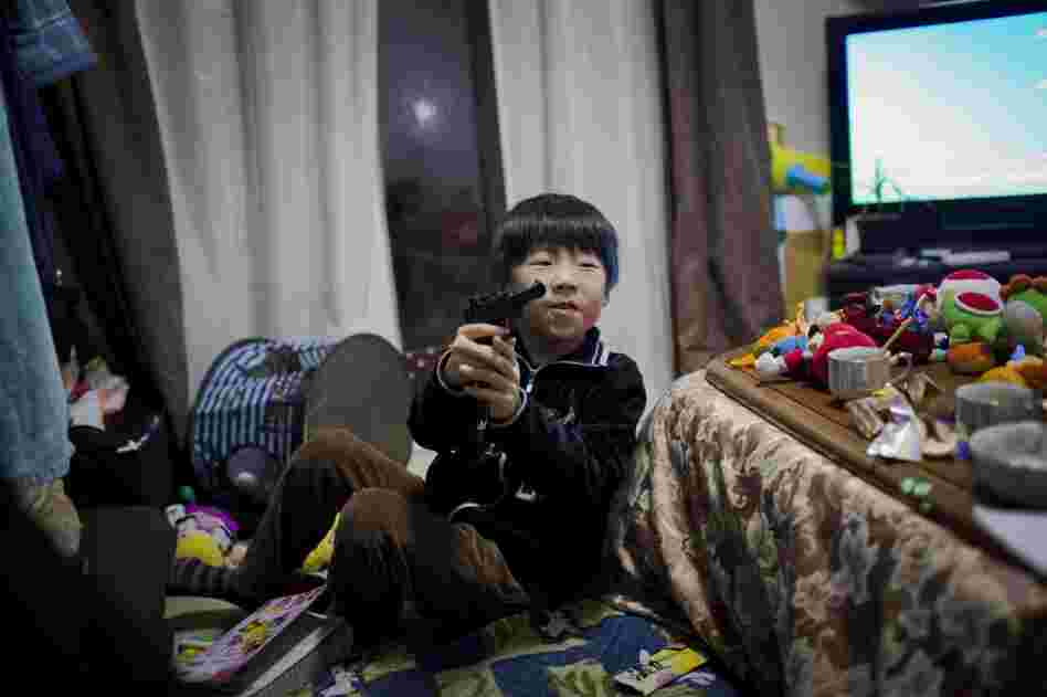 Mitsuhiro Abe, 7, who lives in temporary housing with his grandmother and parents, plays with a toy gun in the family's living room.