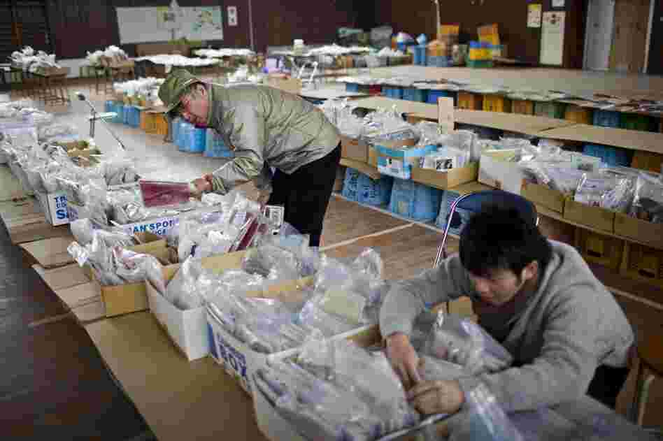 Daisuke Arakawa (right) searches for a photograph of his grandparents, with his uncle Katsuhiko Arakawa, in a school gym set up as a collection site for articles found after the tsunami, in the Yuriage area of Natori, Japan.