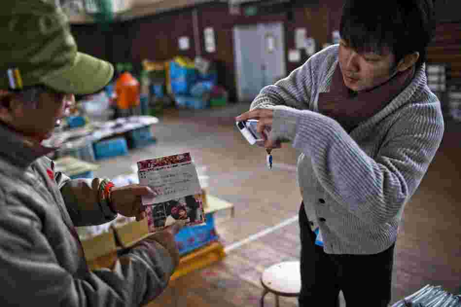 Katsuhiko Arakawa holds up a family album belonging to his parents while Daisuke takes a photo. "They were elated," says photographer Daniel Berehulak. "They left that morning with a trove of memories."