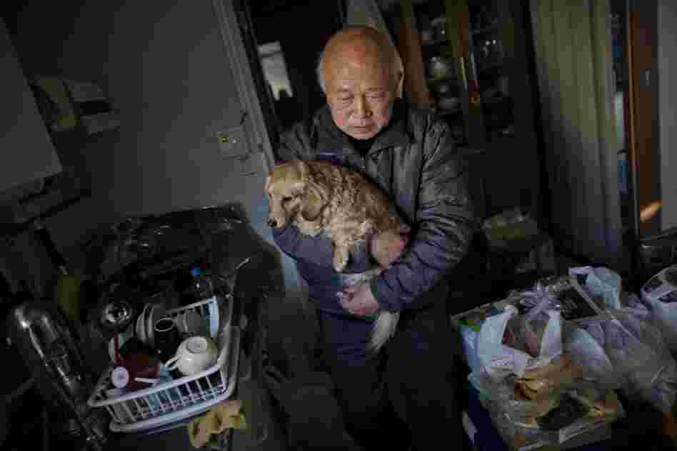 Koichi Matsumoto's home was destroyed. Here, the 74-year-old holds his dog, Jyonko, as he walks through his temporary housing unit.