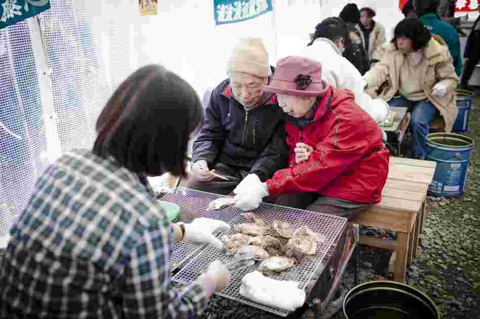 Shiro Uwano, 82, and Reiko Uwano, 76, eat charcoal grilled oysters at Ishinomaki's only functioning restaurant. On this day, the wait for a seat was more than hour.