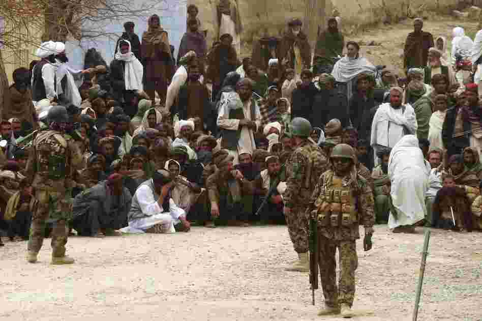 Afghan National Army soldiers keep watch as Afghans gather outside a U.S. base in Panjwai district Kandahar province. 