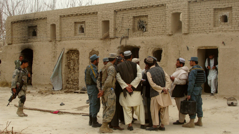 Afghan civilians and soldiers gather outside a home where Afghans were shot dead on Sunday, allegedly by a U.S. serviceman, in the Panjwayi district in southern Afghanistan.
