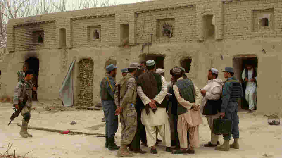 Afghan civilians and soldiers gather outside a home where Afghans were shot dead on Sunday, allegedly by a U.S. serviceman, in the Panjwayi district in southern Afghanistan.