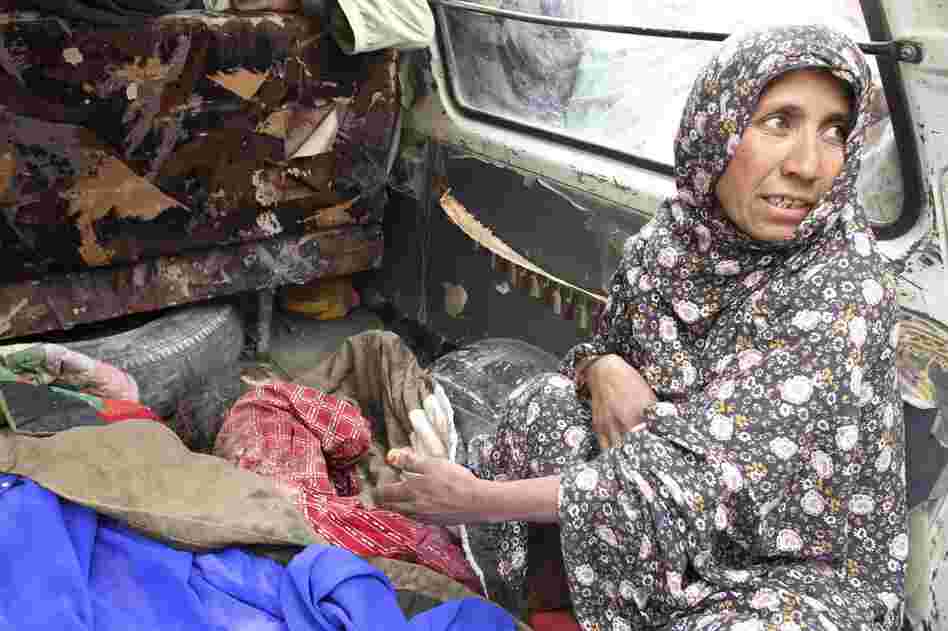 As one woman spoke to reporters, she pulled back a blanket to reveal the body of a smaller child. A third dead child lay amid a pile of green blankets in the bed of a truck. 