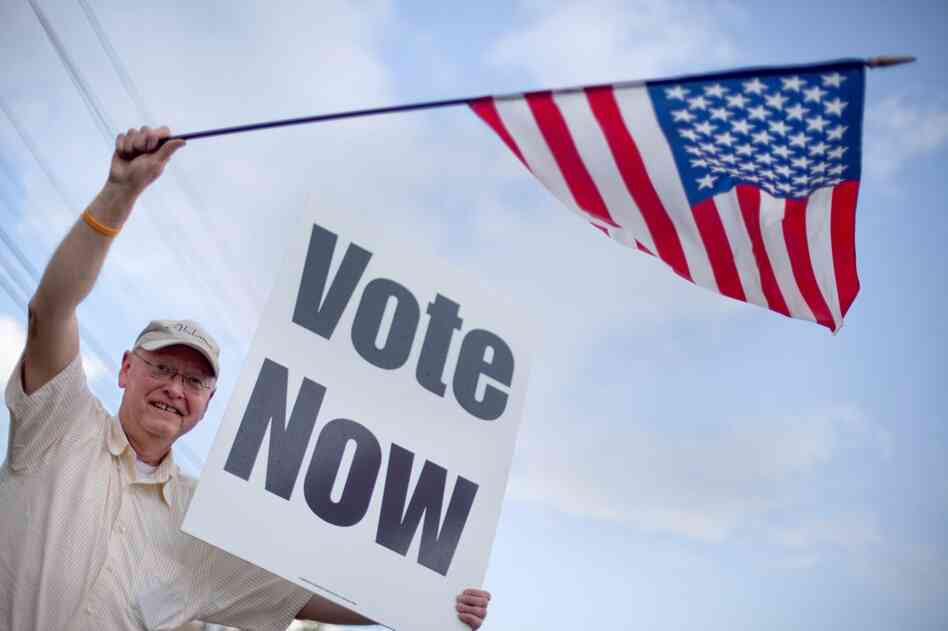 Danny Cooper of Chilton County, Ala., waves to motorists outside a polling place. 