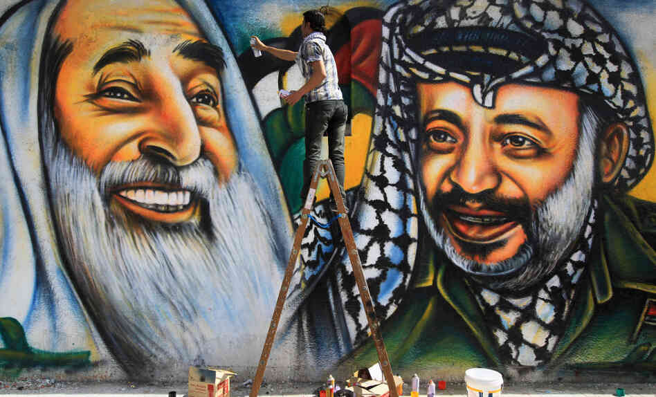 Palestinian artist Mohammed al-Dairi paints a mural of late Palestinian leader Yasser Arafat (right) and late Hamas leader Sheikh Ahmed Yassin (left), in Gaza City. Hamas leaders are divided on what direction to take the Islamist movement, with some calling for reconciliation with Arafat's Fatah movement.