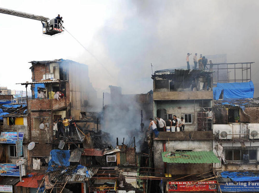 Indian fire brigade officials use water jets to control a fire in the Garibnagar slums.