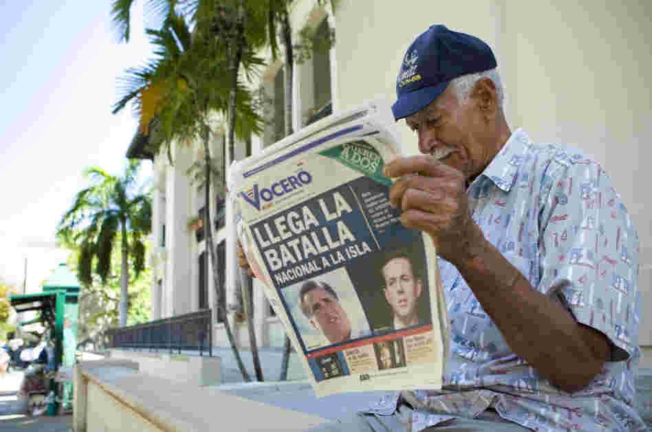 Carlos Diaz, 84, reads local newspaper "El Vocero" with a front page depicting both Mitt Romney and Rick Santorum and a headline reading, "The National Battle Arrives on the Island." 
