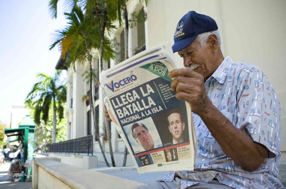 Carlos Diaz, 84, reads local newspaper "El Vocero" with a front page depicting both Mitt Romney and Rick Santorum and a headline reading, "The National Battle Arrives on the Island." 