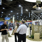 A vendor talks to attendees at the  Border Security Expo in Phoenix, Ariz., next to a display of sophisticated cameras and sensors painted to blend into the desert.