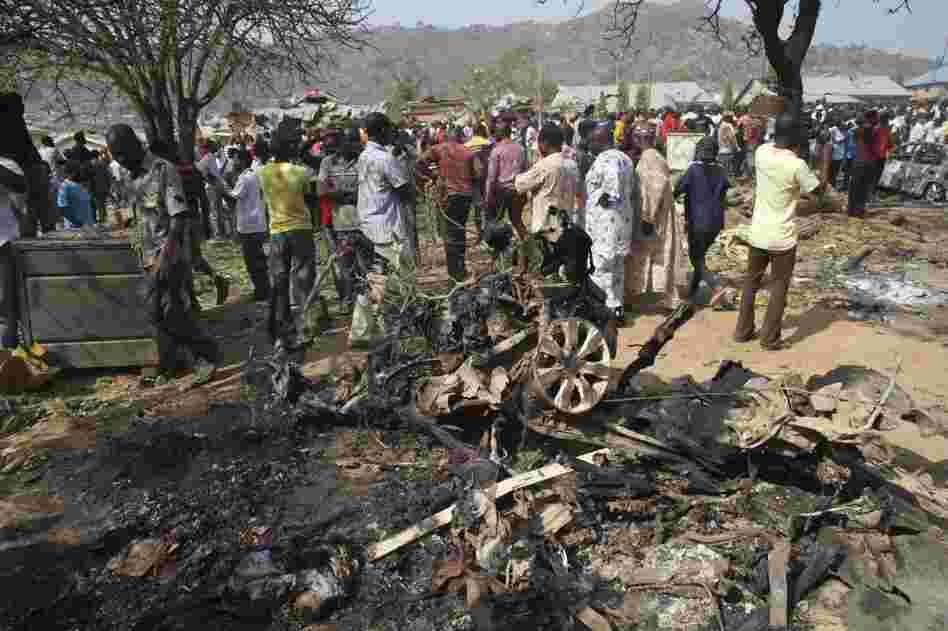 Onlookers view the wreckage of a car bomb that exploded outside a church near Madalla, Nigeria on Christmas Day, 2011 killing scores of people. Boko Haram claimed responsibility for the attack.