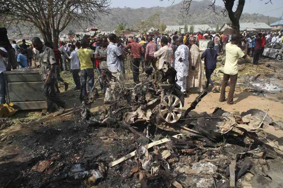 Onlookers view the wreckage of a car bomb that exploded outside a church near Madalla, Nigeria on Christmas Day, 2011 killing scores of people. Boko Haram claimed responsibility for the attack.