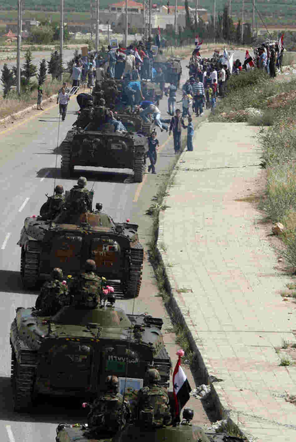 Syrian army troops drive out of the southern city of Daraa on May 5, following a crackdown on protests. 