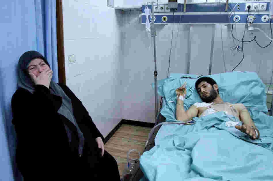A woman weeps next to a man injured in clashes in the port city of Latakia on March 27. 