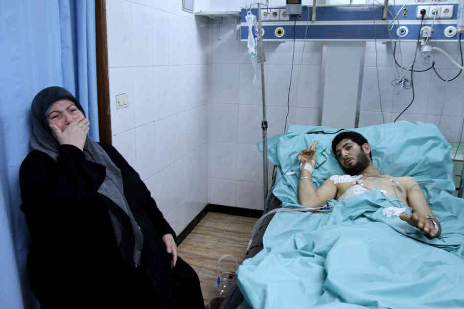 A woman weeps next to a man injured in clashes in the port city of Latakia on March 27. 
