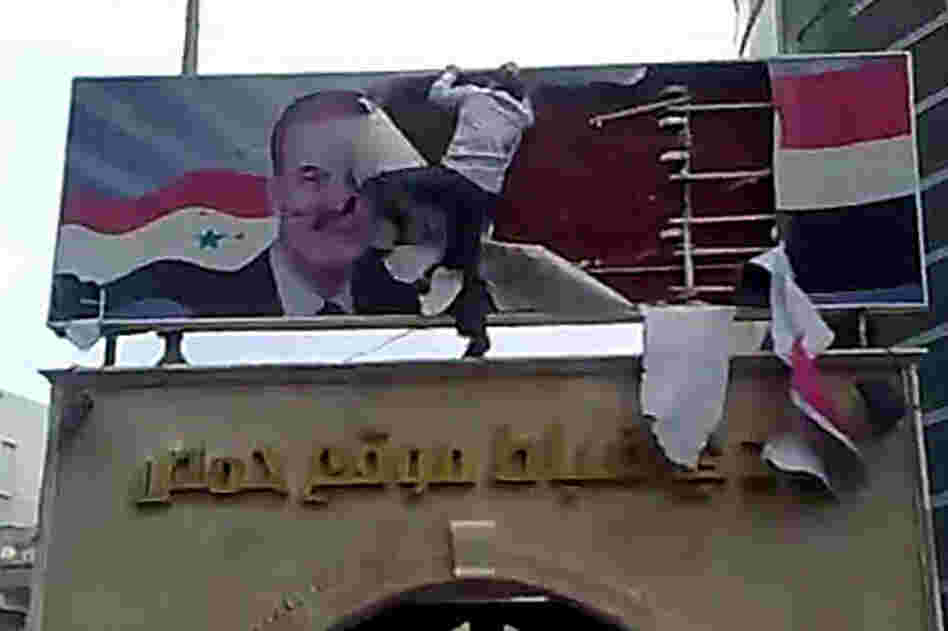 A protester in Homs tears up a poster of ex-president Hafez Assad, who died in 2000, in this AFP image grab from YouTube on March 25. 