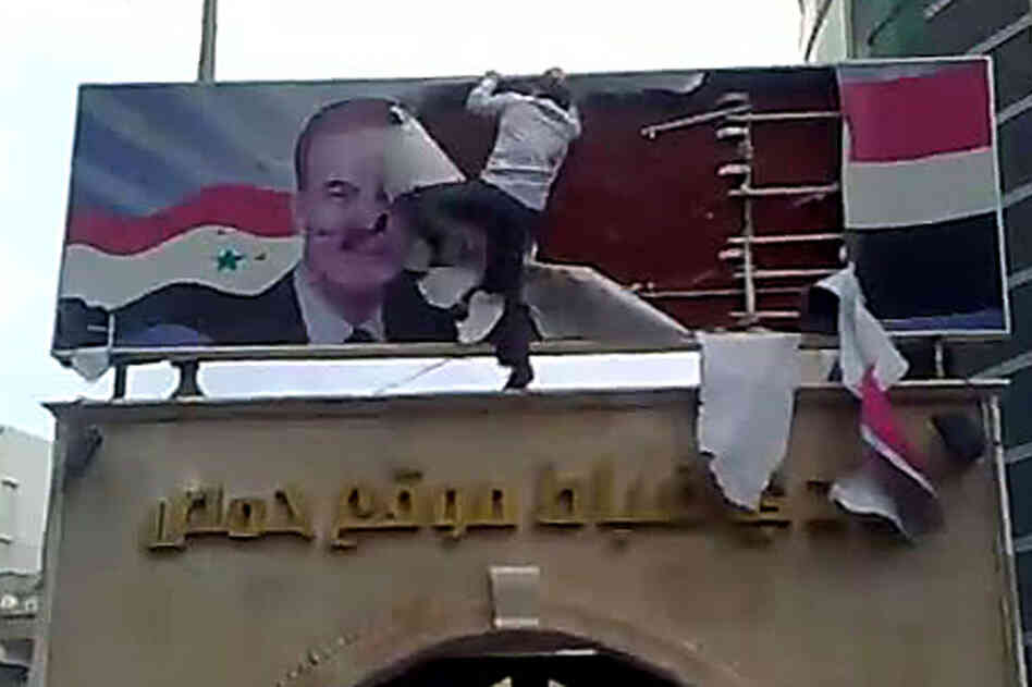 A protester in Homs tears up a poster of ex-president Hafez Assad, who died in 2000, in this AFP image grab from YouTube on March 25. 